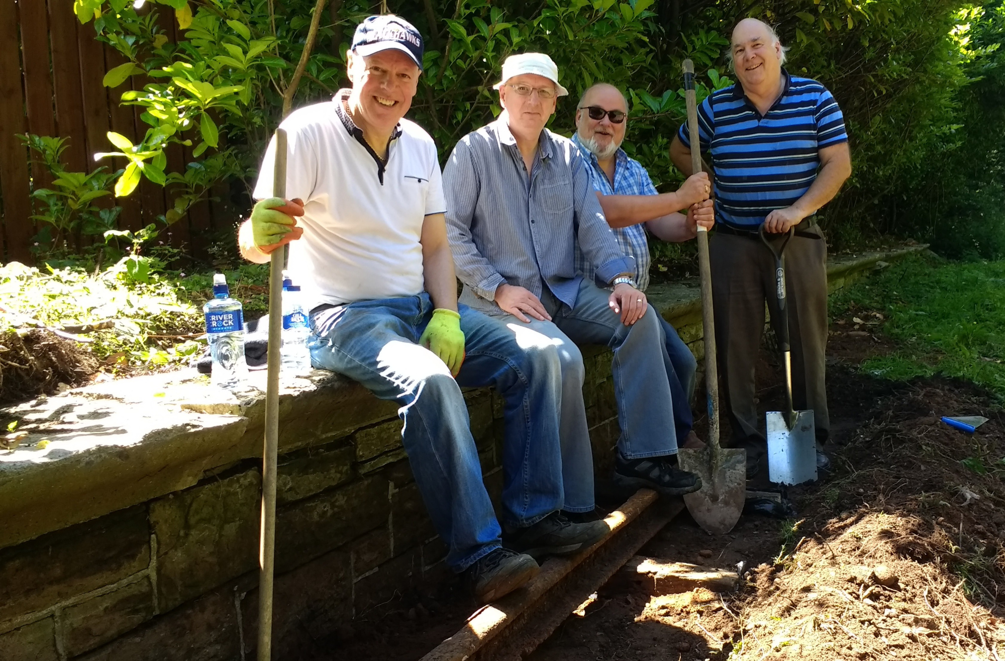 Four men sitting in the old railway platform after cleaning and tending to it.